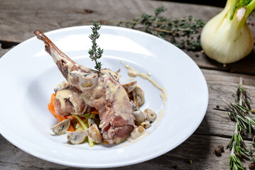 fried rabbit leg in creamy sauce on a plate on a wooden background