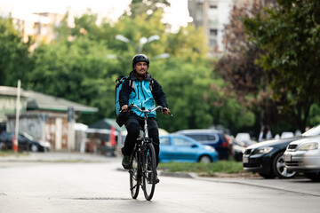 Deliveryman riding bicycle carrying backpack delivering food in city