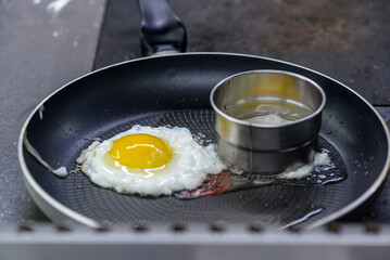 The chef is frying an egg in a frying pan.