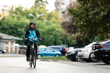 Fototapeta premium Delivery man riding bicycle on city street delivering food