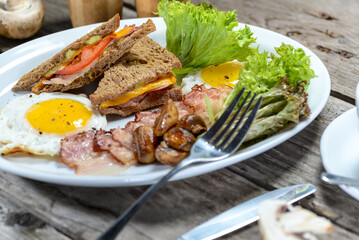 big breakfast egg bacon sandwich and mushroom salad in a white plate