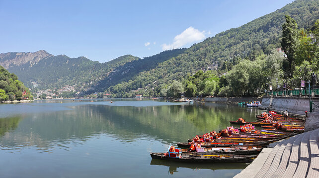Scenic vista of Naini Lake featuring wooden boats, situated in Nainital, Uttarakhand, India.