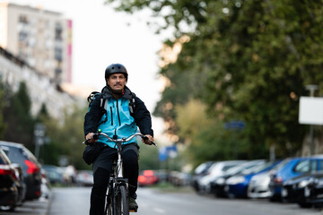 Naklejka premium Delivery man riding bicycle on city street delivering food