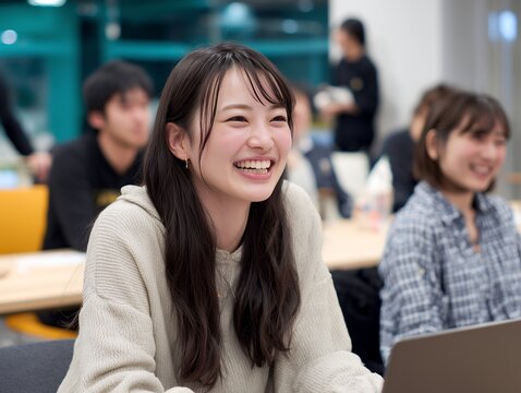 笑顔でパソコンを使う女子学生が教室で学ぶシーン