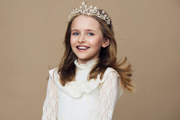 Smiling girl wearing a crown, showcasing joy and innocence against a neutral background, perfect...