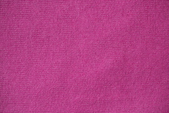pink texture of knitted wool fabric as a background, smooth symmetrical lines of hand-knitted needlework pattern	
