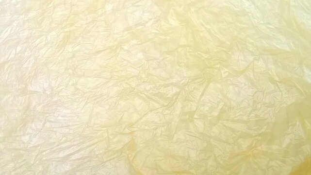Light Yellow crumpled plastic bag texture background rotating. Real Low-Density Polyethylene shopping bag. LDPE shopper texture. vertical clip