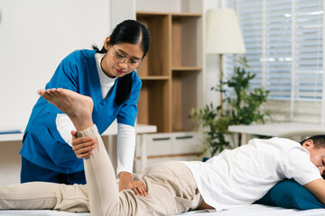 senior man doing exercise at clinic with physiotherapist. help of a personal trainer during a...
