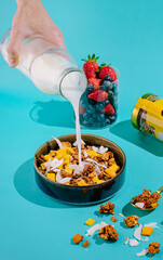 Delicious morning granola bowl with fresh fruit and milk pouring