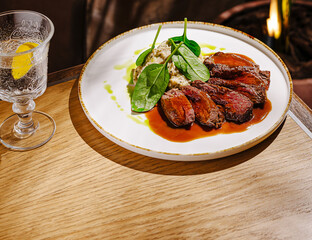 Deliciously prepared beef dish with fresh spinach near a glass of water