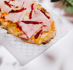 Delicious flatbread topped with ham and sun-dried tomatoes on a plate