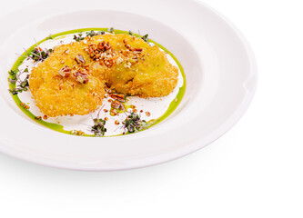 Delicious fried dish garnished with nuts and herbs on a white plate