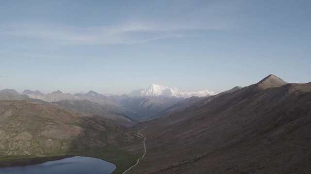 Clear sky view of Nanga Parbat from Deosai National Park with Sheosar Lake, dirt road, and surrounding mountains. Pakistan