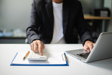Man counting coins on calculator taking from the piggy bank. hand holding pen working on calculator to calculate on desk