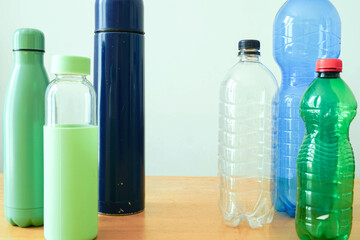 Different water bottles including plastic and reusable types on table. Environmental issue of pollution and waste management. Symbol of daily consumer habits, sustainability awareness, eco lifestyle