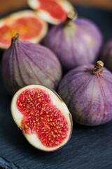 Top view of fresh ripe figs and fig halves on a slate board with natural light. Perfect for healthy...