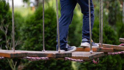 Child on wooden rope bridge in adventure park