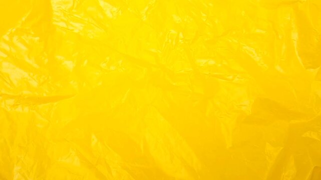 Yellow crumpled plastic bag texture background rotating. Real High-Density Polyethylene shopping bag. HDPE shopper texture.