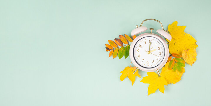 Winter time changeover, end of daylight saving time in autumn, alarm clock fall back switch, colorful foliage