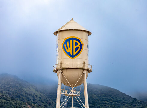 Burbank, USA, Mar 12, 2023 &ndash; The iconic Warner Bros. water tower featuring the WB logotype on the studio lot in California, with low clouds and green hills in the background.
