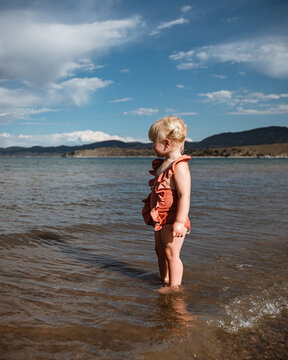 Naklejki Little girl standing in shallow water on shore of Green River