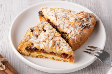A plate holds two slices of a delicious pastry topped with powdered sugar.