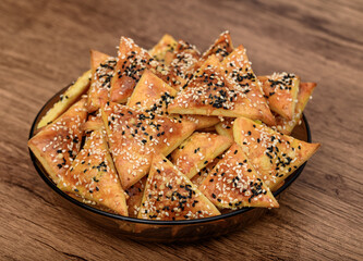 A plate full of crackers for a party, a homemade baked snack sprinkled with sesame seeds and black cumin