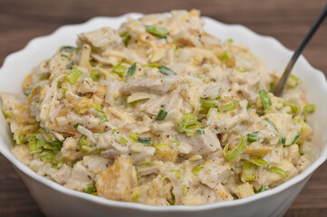Macro close-up of a salad in a mayonnaise sauce with rice, chicken, pineapple, peach, corn and leek, recipe