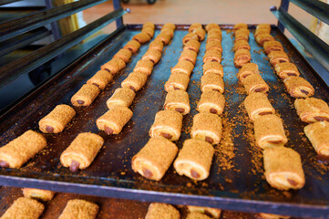 Freshly baked rolled pastries with sweet filling displayed on a baking tray in a cozy bakery setting