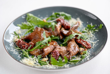 salad with arugula and meat in a plate on a light background
