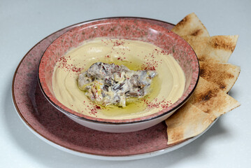 hummus in a plate with decorations on a white background with pita bread