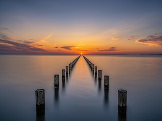 Obraz premium Sunset Over Still Waters Pillars to the Horizons Glow, a Serene Vista.