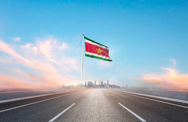 Suriname national flag with mast waving with beautiful skyline. A view from highway. Suriname flag...