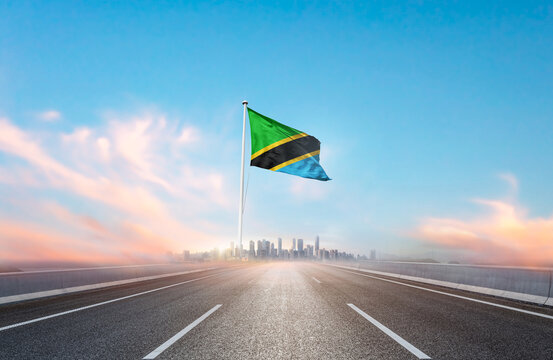 Tanzania national flag with mast waving with beautiful skyline. A view from highway. Tanzania flag for Republic Day and Independence Day. - Powered by Adobe