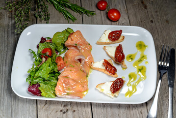 salad with salmon, herbs and bruschetta in a plate on the background