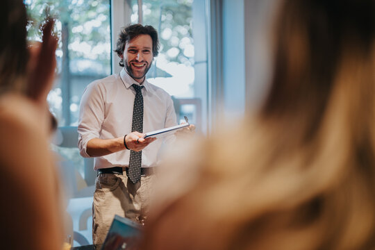 A professional presenter engages a group in an interactive business workshop in a bright, well-lit room. The setting conveys collaboration and effective communication in a professional setting.