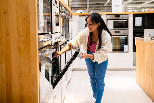 Womanshopping for oven in modern appliance store smiling