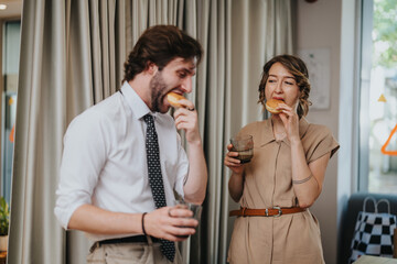 A man and a woman in a relaxed office setting share casual conversations while enjoying donuts and drinks. The scene reflects camaraderie and a lively workplace atmosphere.