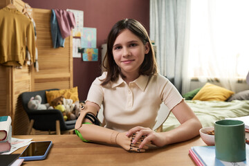 Smiling young girl with prosthesis in home setting looking at camera
