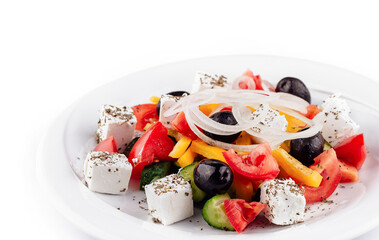 Greek salad with feta cheese, olives, and vegetables on white plate