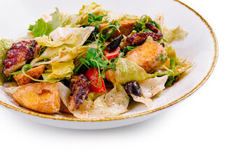 Fresh salad with grilled octopus, lettuce and croutons lying on white plate