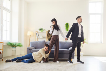 Desperate man clings to woman leg as she leaves with another man, creating powerful image of...