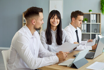 In an office, colleagues show teamwork: review documents, join a discussion, and lead planning at a...