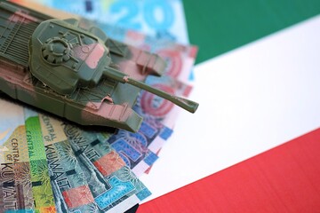 Kuwaiti dinar currency money bills and toy tank on flag. The concept of army funds and weapons sales
