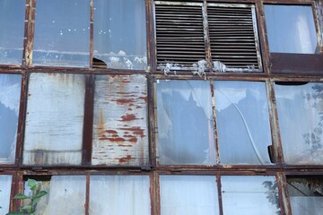 Old building with rusty metal frames and broken windows — symbol of decay, time, and urban...