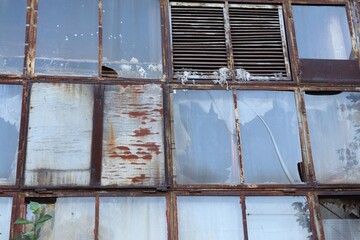 Old building with rusty metal frames and broken windows — symbol of decay, time, and urban...