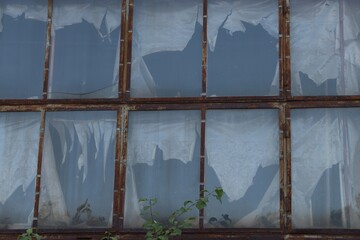 Old building with rusty metal frames and broken windows — symbol of decay, time, and urban...