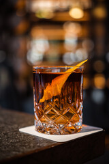 Negroni cocktail on the bar, bo. equal parts gin, vermouth rosso, and Campari, garnished with an orange peel.