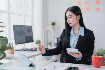 Young businesswoman using stylus pen and digital tablet while holding calculator, analyzing...