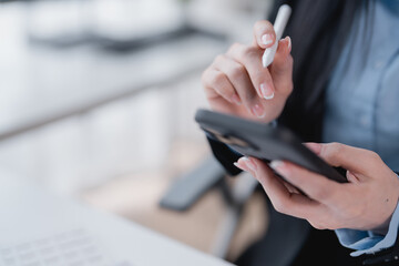Businesswoman using a stylus pen on her smartphone in an office setting, highlighting the...